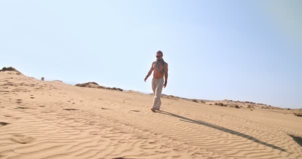 Mladý muž se steampunkovými brýlemi kráčející sám v poušti — Stock video