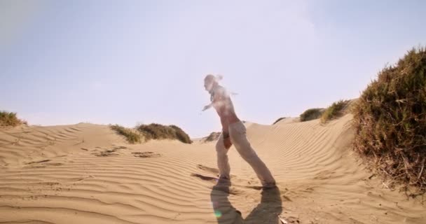 Молодий атлетичний чоловік робить стрибок назад на пісок у зворотному напрямку — стокове відео