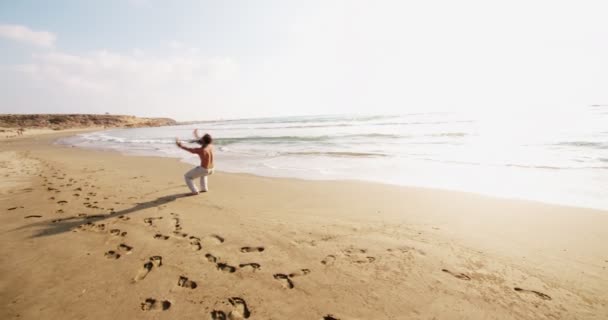 Joven atleta masculino parkour haciendo volteretas en la playa — Vídeos de Stock