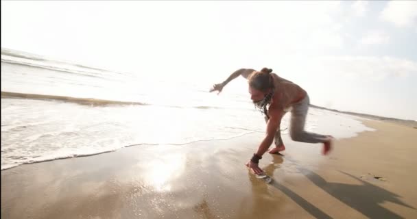 Jonge gespierde man doet capoeira backflip op het strand — Stockvideo