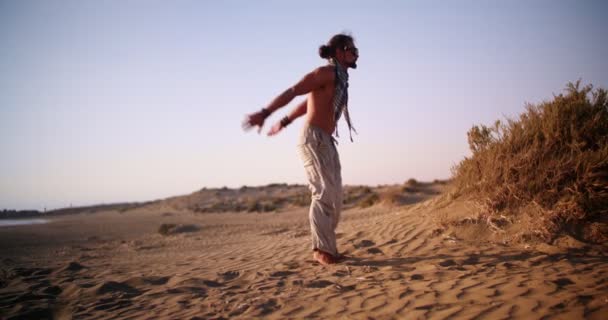 Молодий м'язистий чоловік робить стрибок назад на пляжному піску — стокове відео