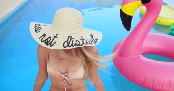 Jeune femme avec chapeau à la mode relaxant près de la piscine avec des inflatables — Video