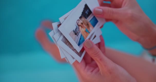 Junge Frau blickt auf Sommererinnerungen Sofortfotos am Pool — Stockvideo