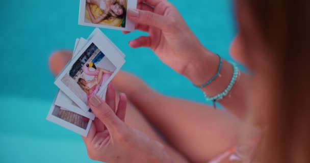 Woman sitting by pool looking at summer holidays polaroids — Stock Footage Woman sitting by pool looking at summer holidays polaroids Stock Footage