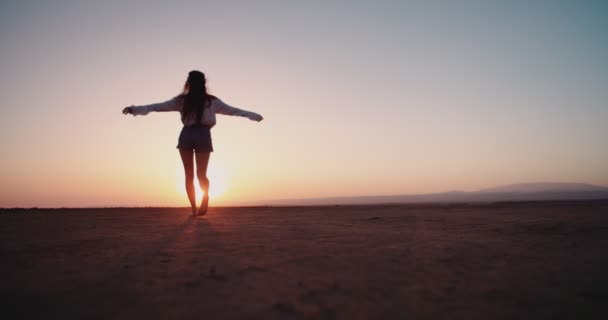 Ung kvinna på semester går barfota i öknen vid solnedgången — Stockvideo