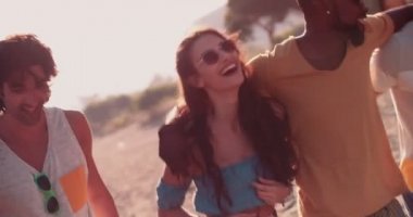 Genç çok ırklı hippi arkadaşlar yazın sahilde yürüyorlar.