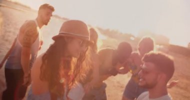 Günbatımında plaj partisinde dans eden çok ırklı hippi arkadaşlar.