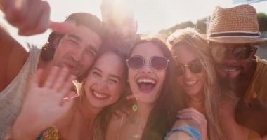 Genç, çok ırklı hipster arkadaşlar sahilde video oyunu oynuyorlar.