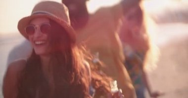 Plaj partisinde dans eden ve bira içen çok ırklı genç hippiler.