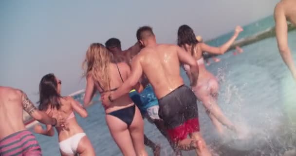 Молодые многонациональные друзья на летних каникулах, бегущие в море — стоковое видео