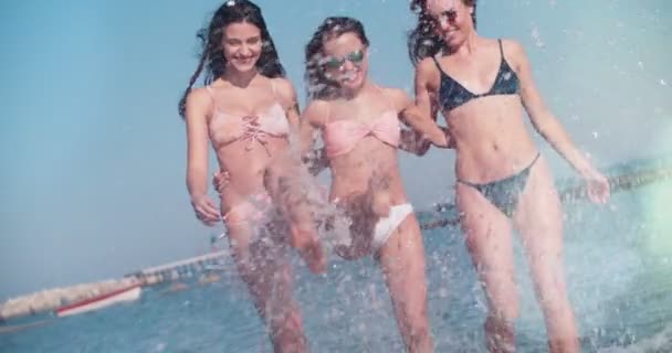 Unga kvinnor på sommarlov stänk vatten på stranden — Stockvideo