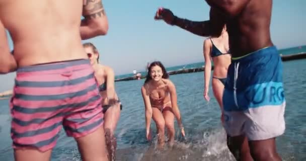 Young multi-ethnic people having fun splashing water at the beach — Stock Video