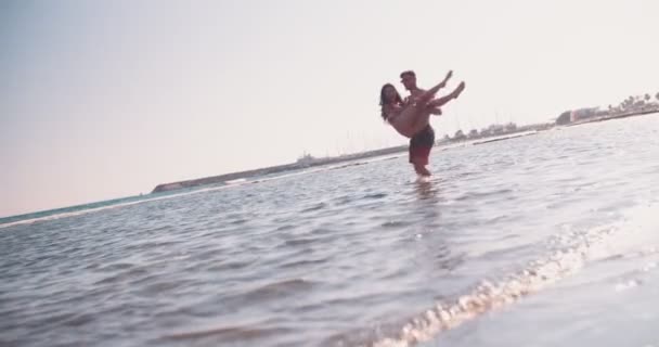 Jongeman houden vriendin en spinnen haar in de zee — Stockvideo