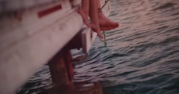 一对浪漫的年轻夫妇坐在海面上的木制码头上 — 图库视频影像