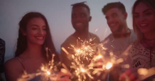 Jóvenes hipsters multiétnicos celebrando con bengalas en la fiesta de verano en la playa — Vídeo de stock