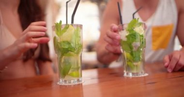 Genç hippi arkadaşlar yaz barında mojito kokteylleriyle kadeh kaldırıyorlar.