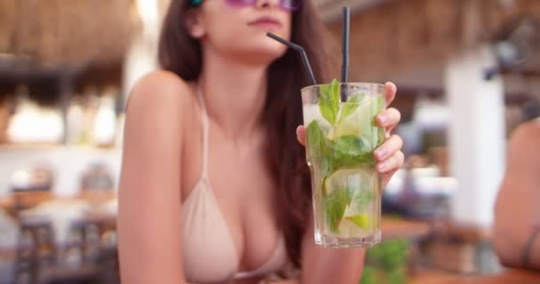 Красивая женщина в бикини пьет коктейль мохито в летнем баре — стоковое видео