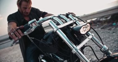 Motorsikletin üzerinde elleri gidonun üzerinde oturan asi bir motorcu.