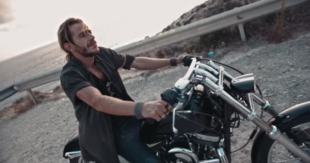 Uomo con i capelli lunghi seduto su moto vintage al tramonto — Video Stock