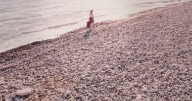 Yazın sahilde yürüyen genç boho kadın.