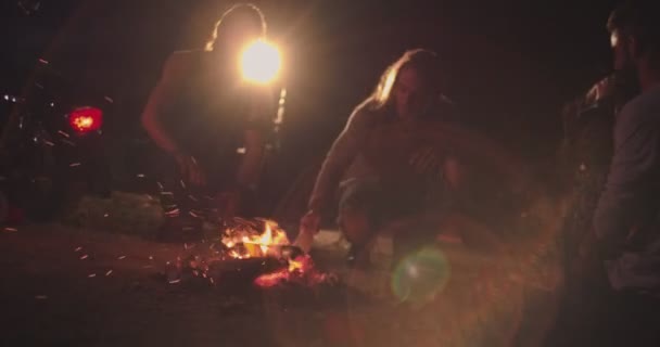 年轻的骑摩托车的反叛者朋友在晚上点燃篝火准备参加聚会 — 图库视频影像