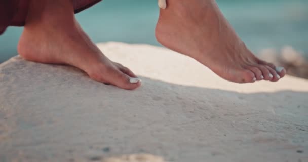 Woman with ankle bracelet walking on beach rock — Stock Video