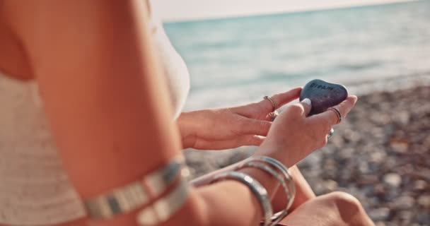 Hipisowska kobieta trzymająca kamień na plaży i marząca o dniu — Wideo stockowe