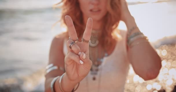 Hippie vrouw maakt een vredesteken op het strand — Stockvideo