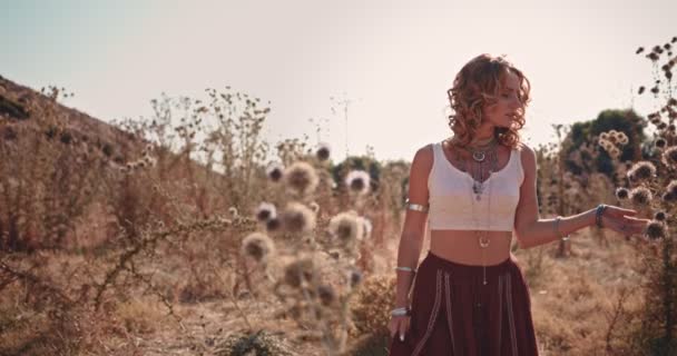 Jong hippie meisje met zilveren sieraden wandelen in het wild bloemen veld — Stockvideo