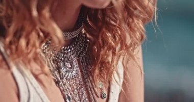 Mücevherleri olan genç bir kadın kumsalda dinleniyor.