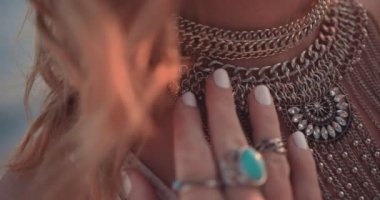 Açık havada gümüş yüzükler takan ve kolye takan bir kadın.