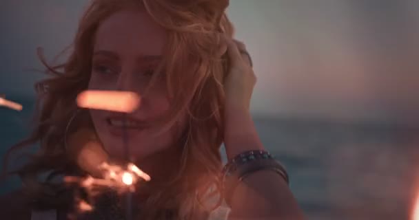 Joven pelirroja hippie mujer con chispas en la playa después del atardecer — Vídeo de stock