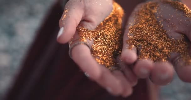Крупный план женских рук хиппи, раздувающих золотой блеск — стоковое видео