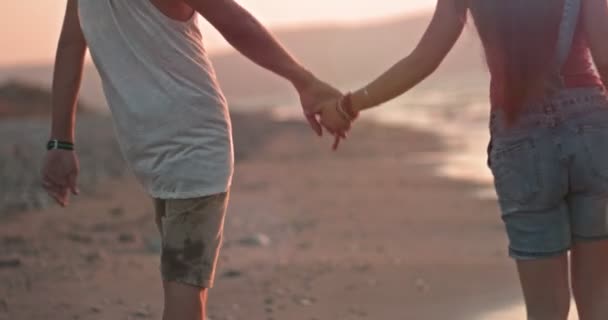 Detailní záběr na mladý pár držící se za ruce na pláži — Stock video