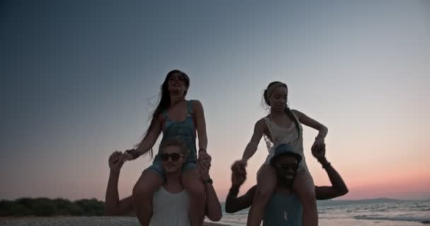 Young multi-ethnic friends and couples giving beach piggy-back rides — Stock Video