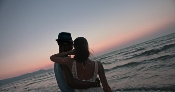Jong romantisch paar op vakantie omarmen op het strand bij zonsondergang — Stockvideo