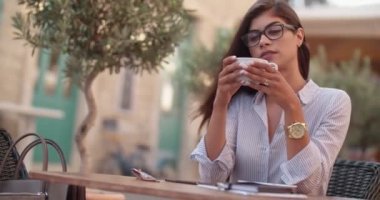 Restoranda kahve içen bardaklı genç bir iş kadını.