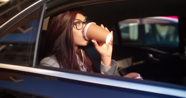 Zakenvrouw die koffie drinkt op de achterbank van een luxe auto — Stockvideo