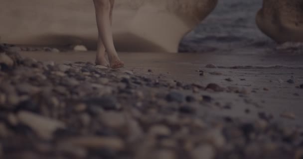 Primer plano de la mujer caminando en la costa al atardecer — Vídeos de Stock