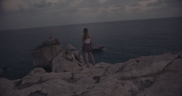 Mulher de pé no alto do penhasco e olhando para o mar — Vídeo de Stock