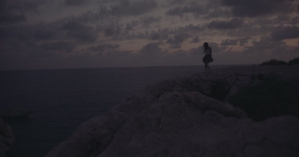 Femme assise sur une falaise rocheuse et regardant l'océan — Video