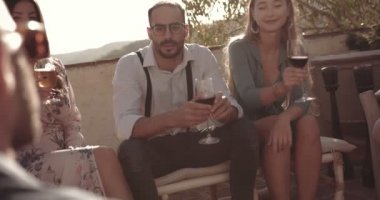 Şarap ve birayla kadeh kaldıran arkadaşlar kır evlerinin avlusunda oturuyor.