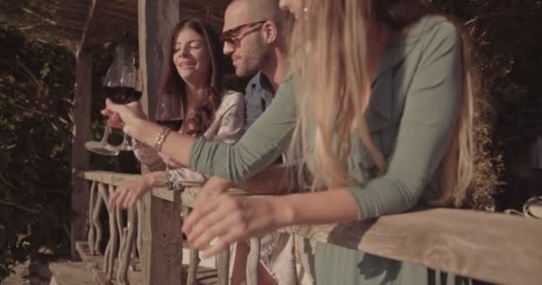 Elegantes amigos brindando con vino tinto en el balcón rústico de la casa — Vídeos de Stock