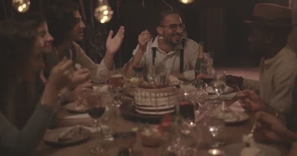 Des amis multiethniques mangent un gâteau d'anniversaire gastronomique lors d'un dîner rustique — Video