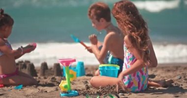 Summner 'da kumsalda kumdan kaleler yapan çok ırklı küçük çocuklar.