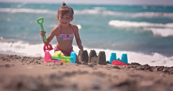 Glückliche chinesische Mädchen spielen auf dem Sand und bauen Sandburgen — Stockvideo