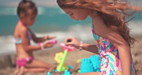 Νεαρά κορίτσια στις καλοκαιρινές διακοπές παίζουν στην άμμο της παραλίας — Αρχείο Βίντεο