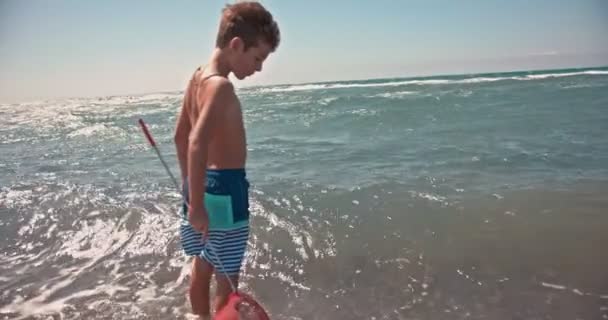 Ung pojke som fiskar med fiskenät vid havet — Stockvideo