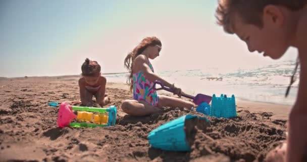 Unga multietniska barn bygga sandslott på stranden sommarsemester — Stockvideo