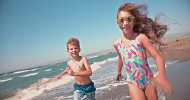 Jong jongen en meisje het hebben van plezier hardlopen op eiland strand — Stockvideo